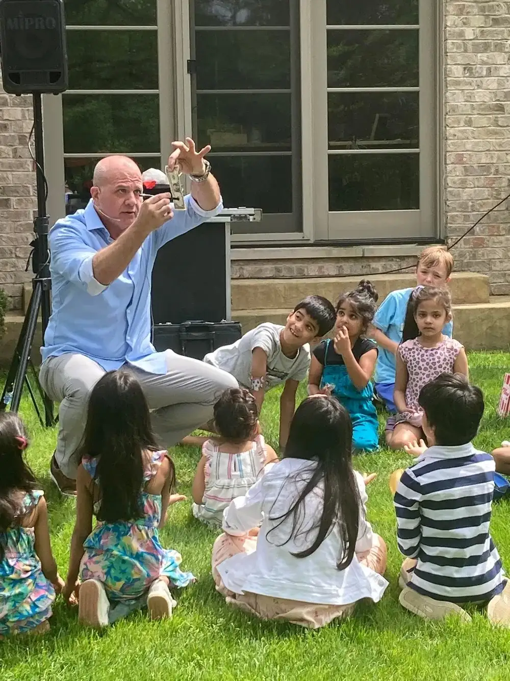 Mike DiDomenico performing money trick for mesmerized children at backyard party