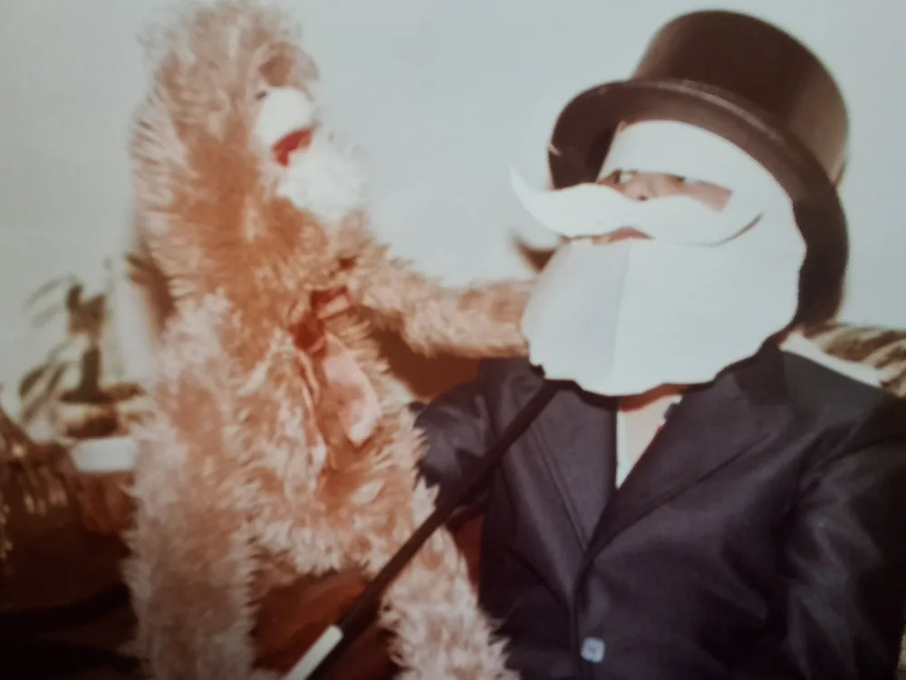 Young Mike DiDomenico as a child in top hat and suit performing magic with a puppet