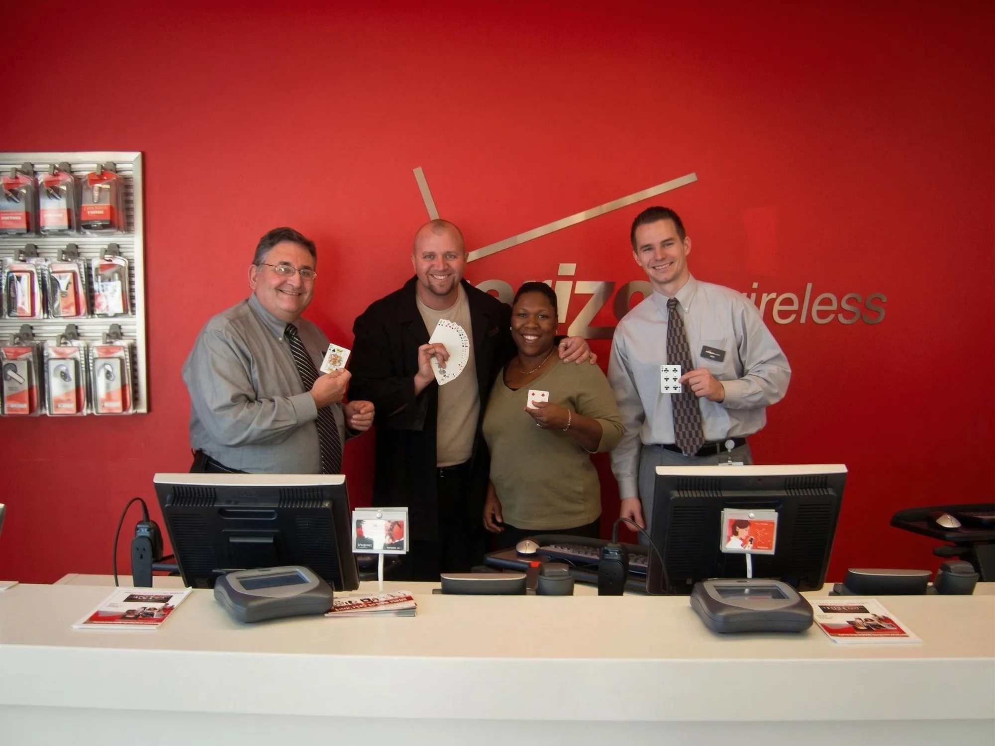 Mike DiDomenico with Verizon Wireless team holding playing cards at corporate event